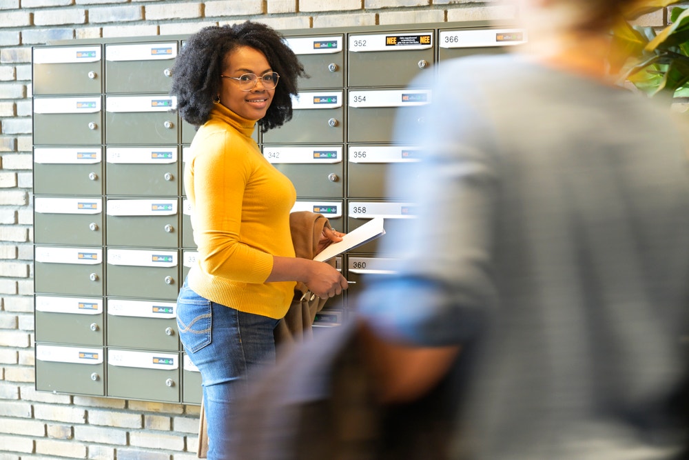 vrouw staat met post bij brievenbus flat
