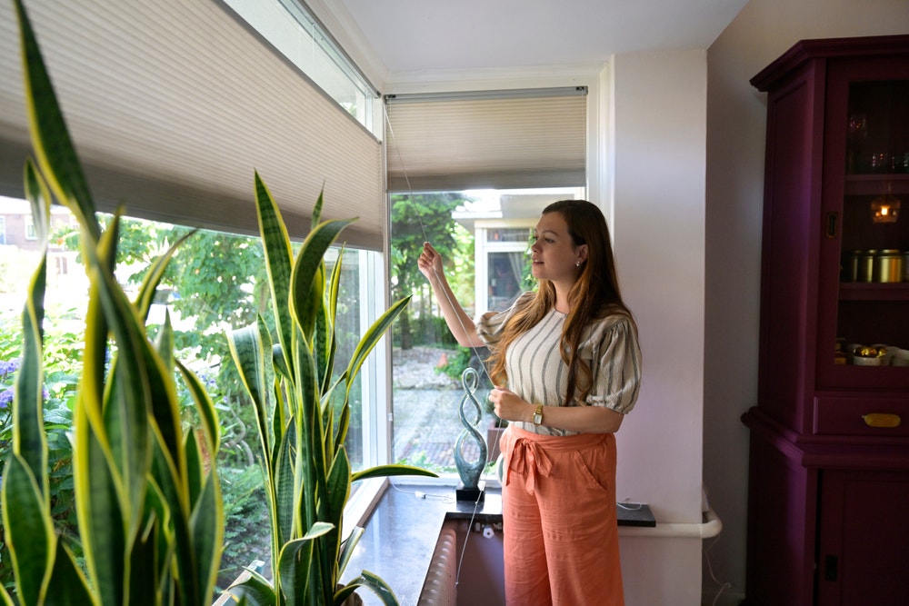 vrouw doet rolgordijn omlaag