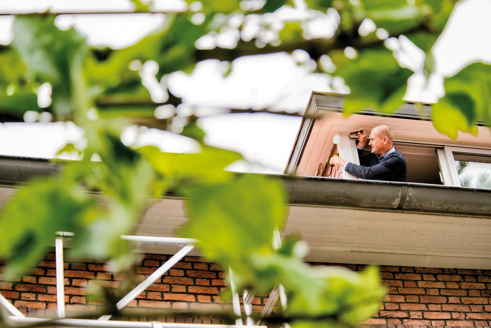 Man leunt uit dakkapel