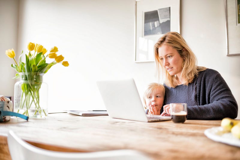 vrouw met kind achter laptop aan tafel