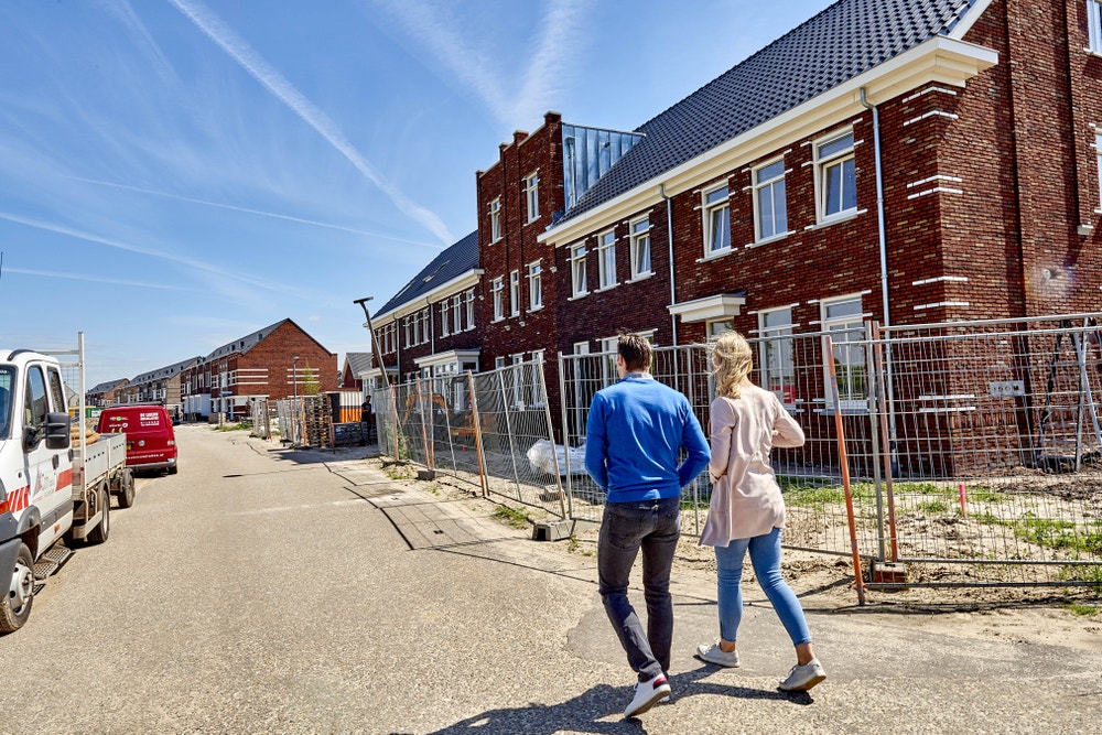 stel loopt over straat bij nieuwbouwwoningen