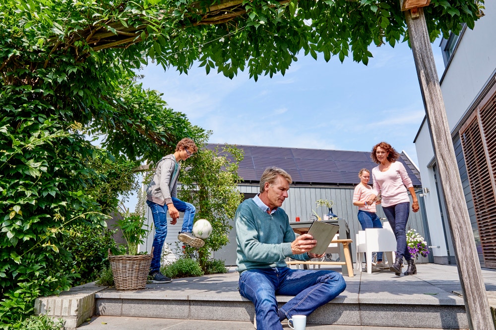 man met tablet in tuin met gezin