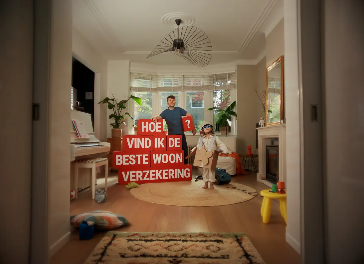 man in woonkamer met rode blokken met de vraag hoe vind ik de beste woonverzekering
