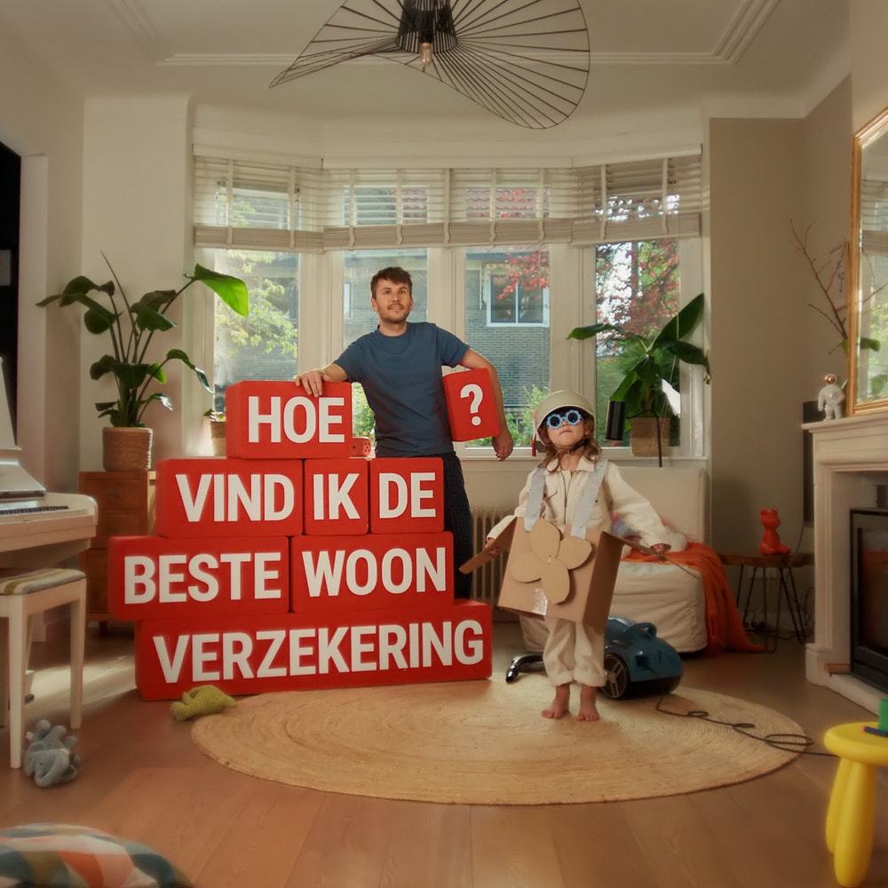 man in woonkamer met rode blokken met de vraag hoe vind ik de beste woonverzekering
