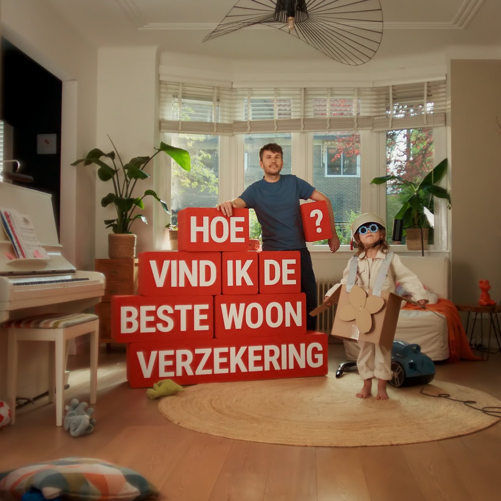 man in woonkamer met rode blokken met de vraag hoe vind ik de beste woonverzekering