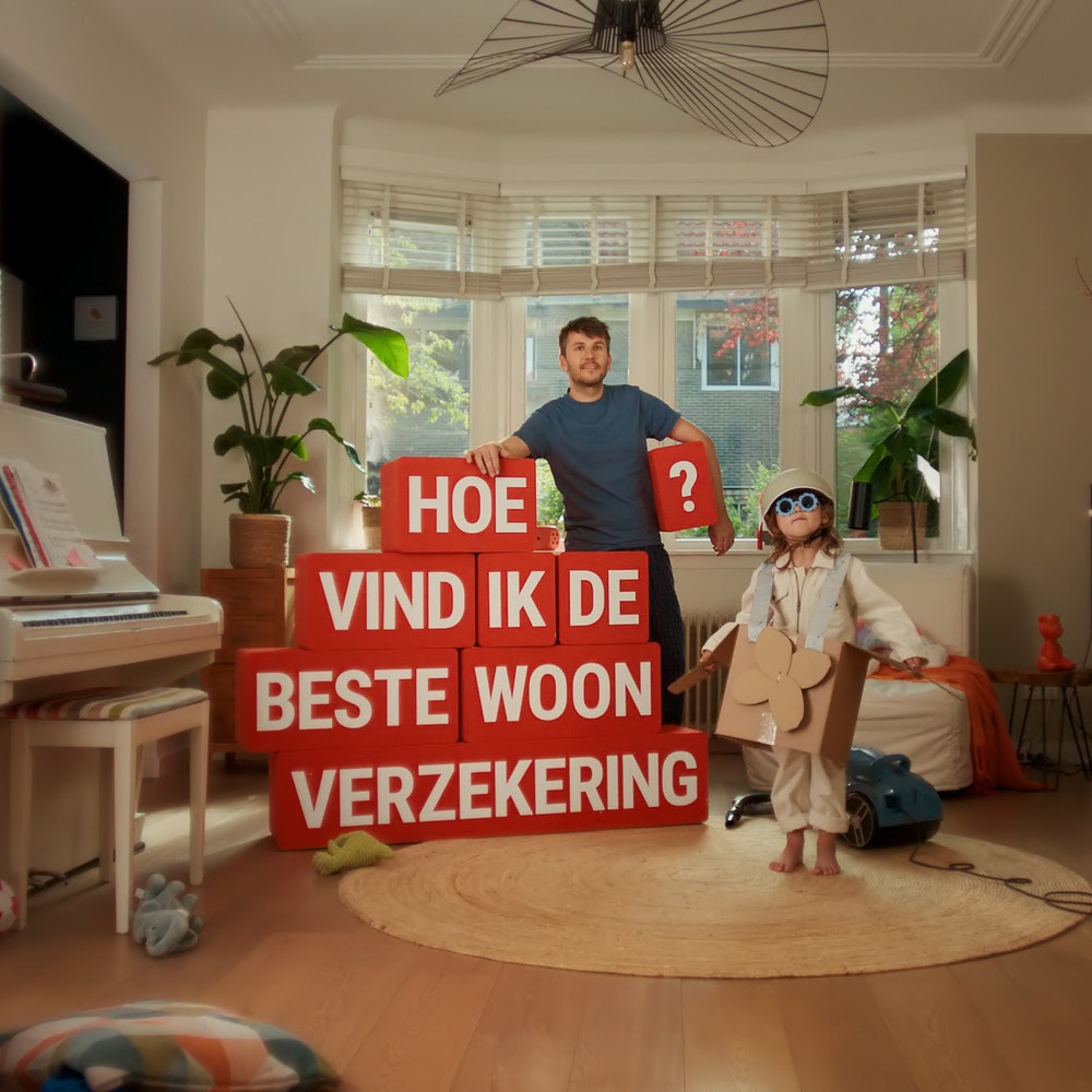 man in woonkamer met rode blokken met de vraag hoe vind ik de beste woonverzekering