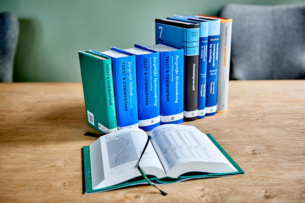 opengeslagen wetboek met daarachter rij boeken