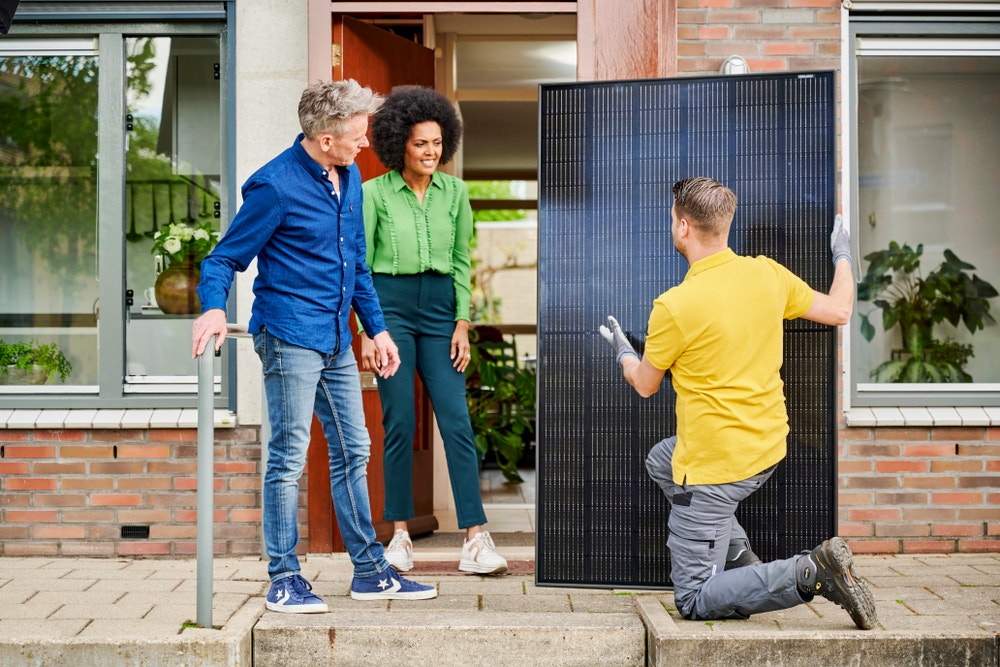 man geeft uitleg aan stel over zonnepaneel bij voordeur