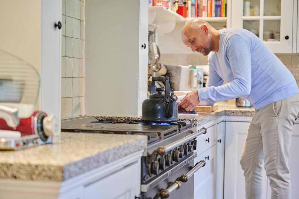 man kookt water op gasfornuis