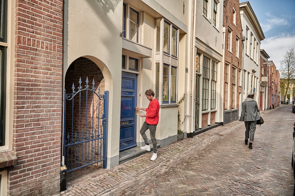 man bij voordeur van oude woning