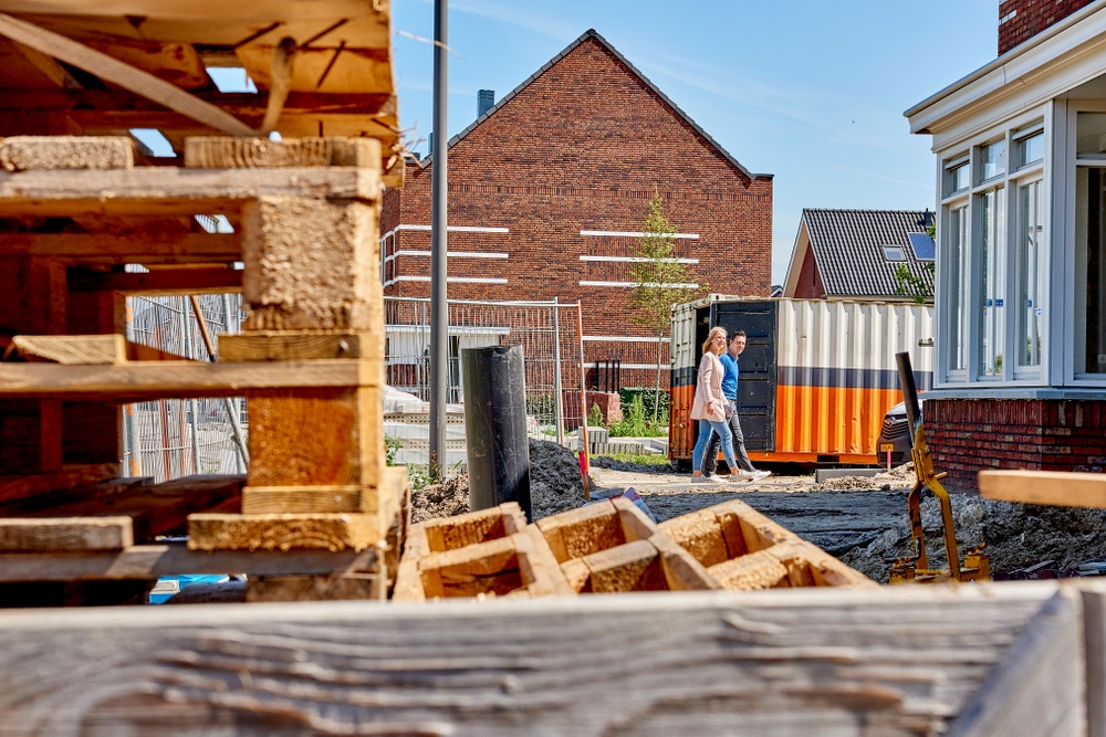 stel loopt over straat nieuwbouwwijk in aanbouw