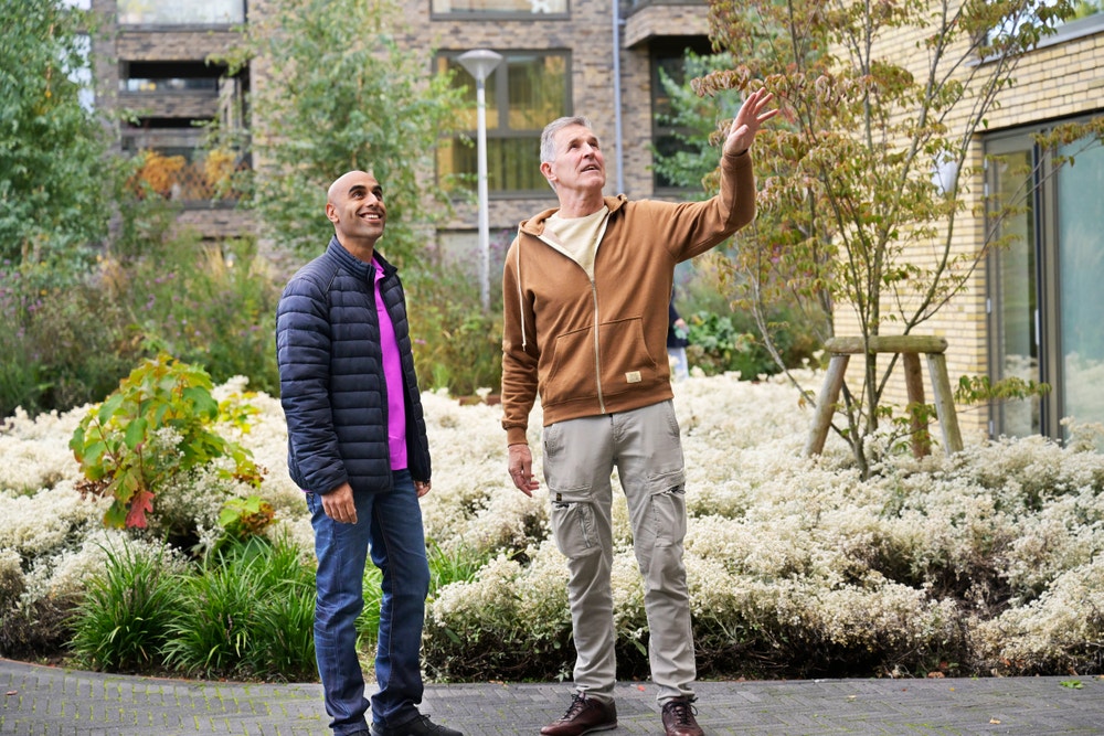 mannen staan in voortuin appartementencomplex