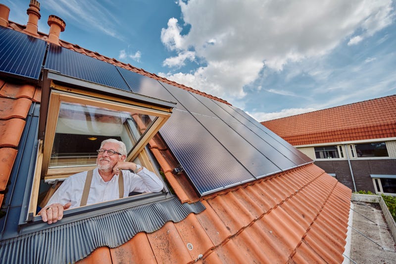 Man kijkt uit raam van dak vol met zonnepanelen