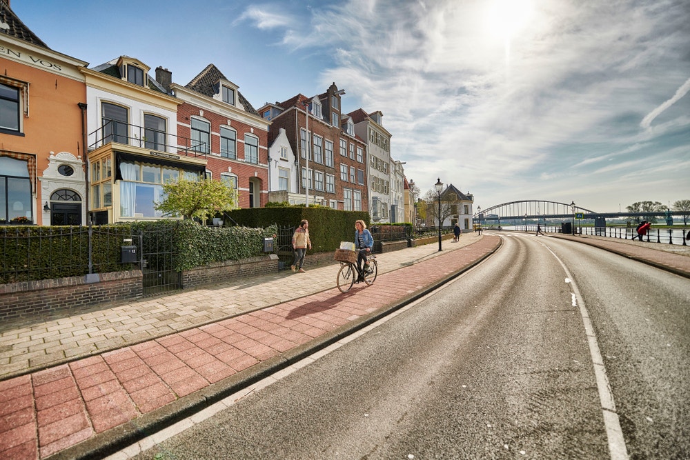 vrouw op fietspad langs weg en oude woningen