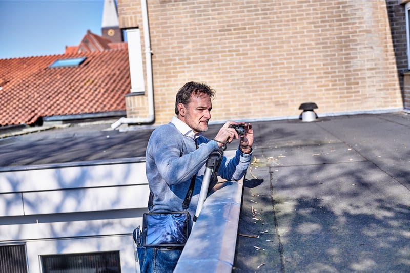Man staat op een ladder en maakt foto's van een dak