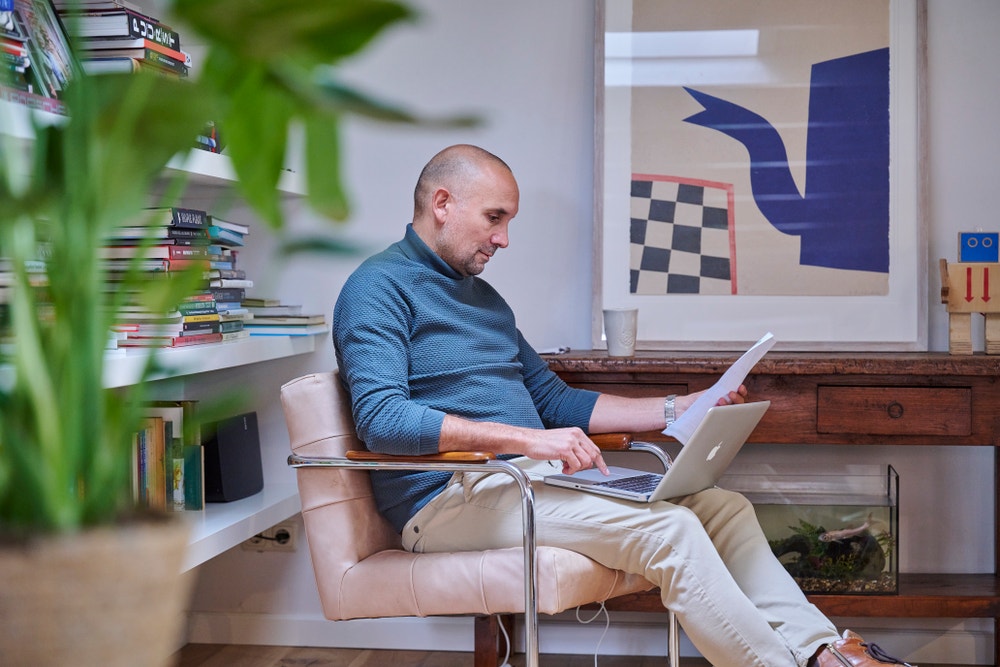 Man zit op een stoel met laptop op schoot.