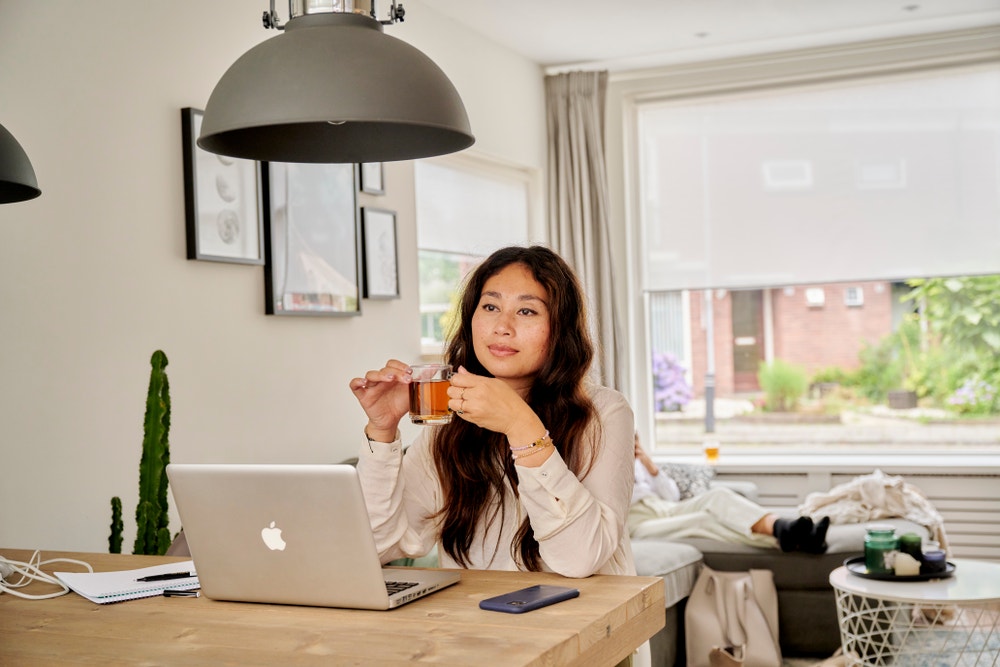 vrouw achter laptop met glas thee