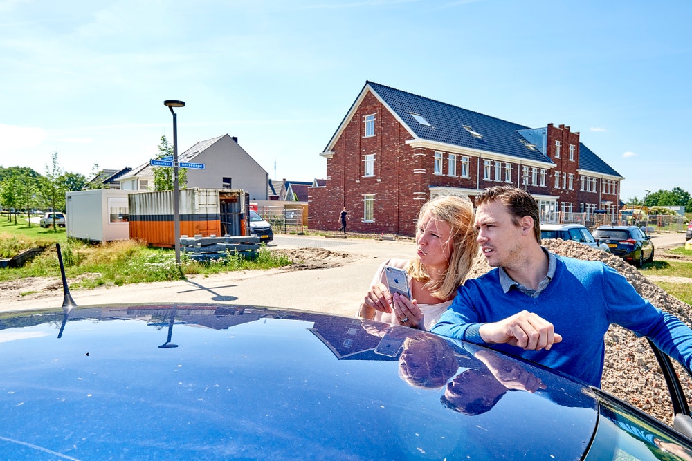 man en vrouw stappen auto uit in wijk in aanbouw