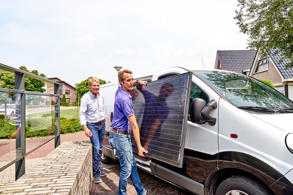 man en zonnepaneleninstallateur tillen zonnepaneel uit busje