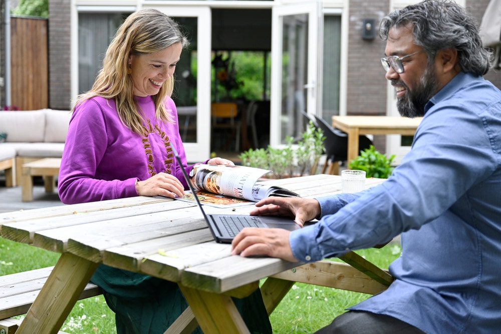 Man en vrouw zitten buiten aan picknicktafel te lezen