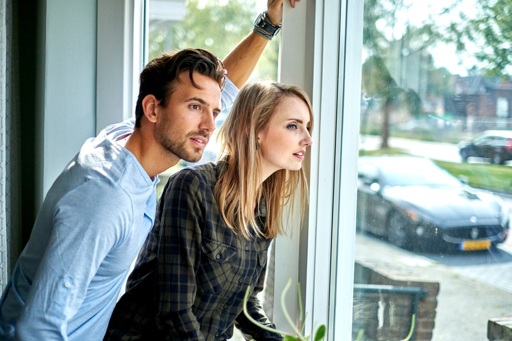 man en vrouw kijken door raam naar buiten