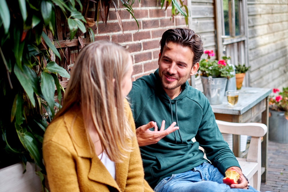 man en vrouw overleggen op bankje in tuin