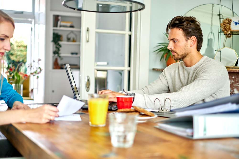 man en vrouw aan tafel met laptop en papierwerk