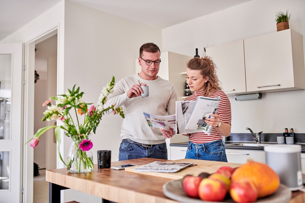 man en vrouw bekijken tijdschriften aan keukentafel