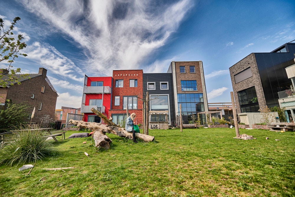 vrouw zit op boomstam op grasveld in woonwijk
