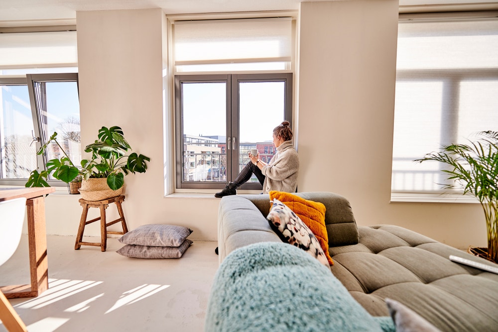 Vrouw zit op vensterbank en kijkt uit raam