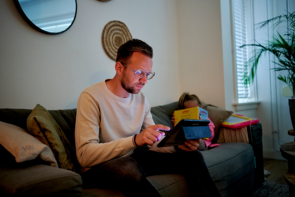 man zit op bank achter tablet