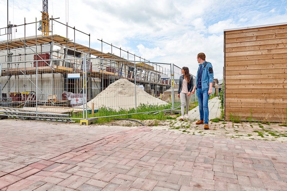 stel loopt langs woning in aanbouw