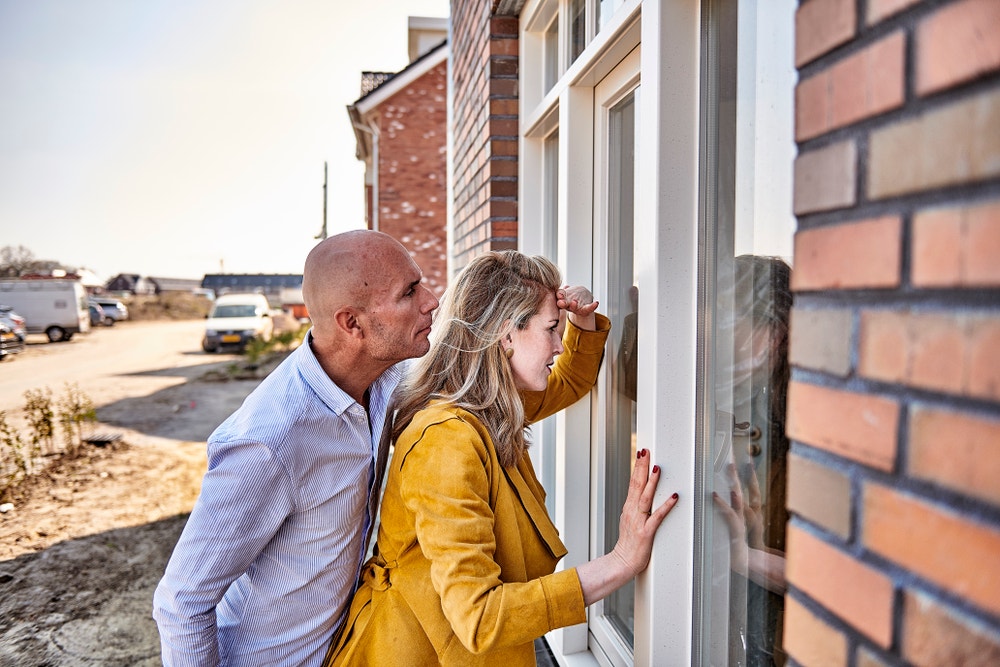 Stel die naar binnen gluurt bij nieuwbouwhuis