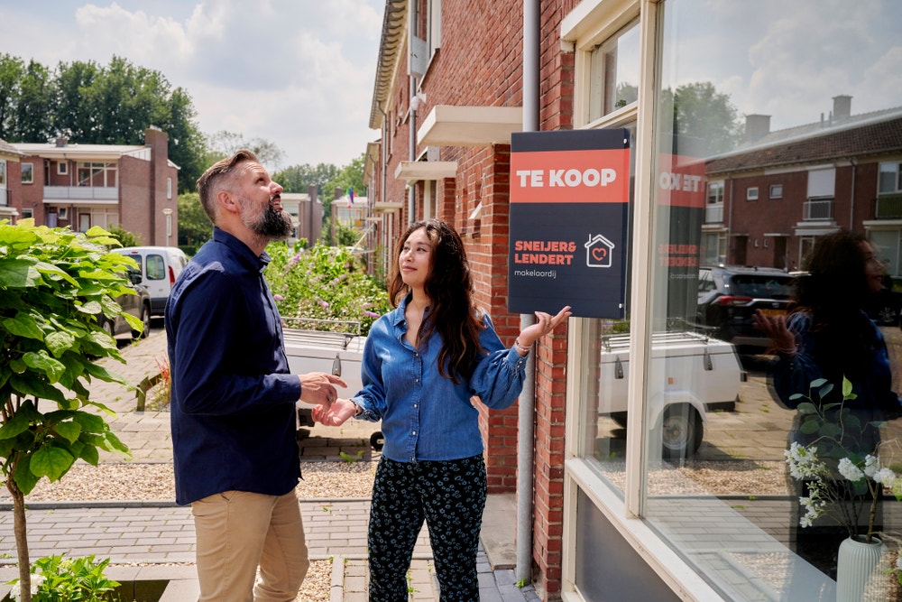 man en vrouw kijken door raam van koophuis