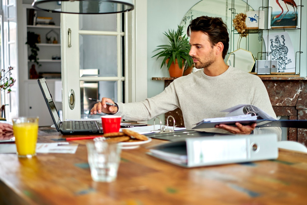 Man zit achter laptop met administratie