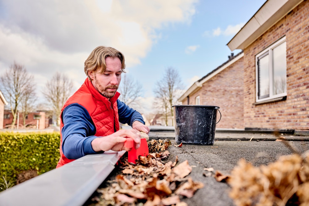 man veegt dakgoot schoon