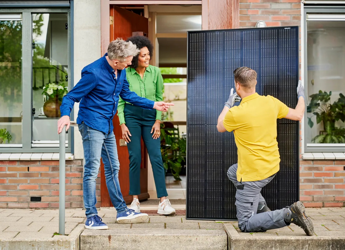 man geeft uitleg aan stel over zonnepaneel bij voordeur