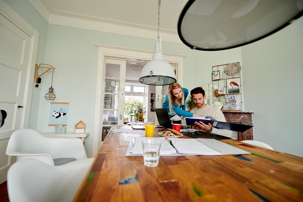 man en vrouw aan tafel met papierwerk en laptop