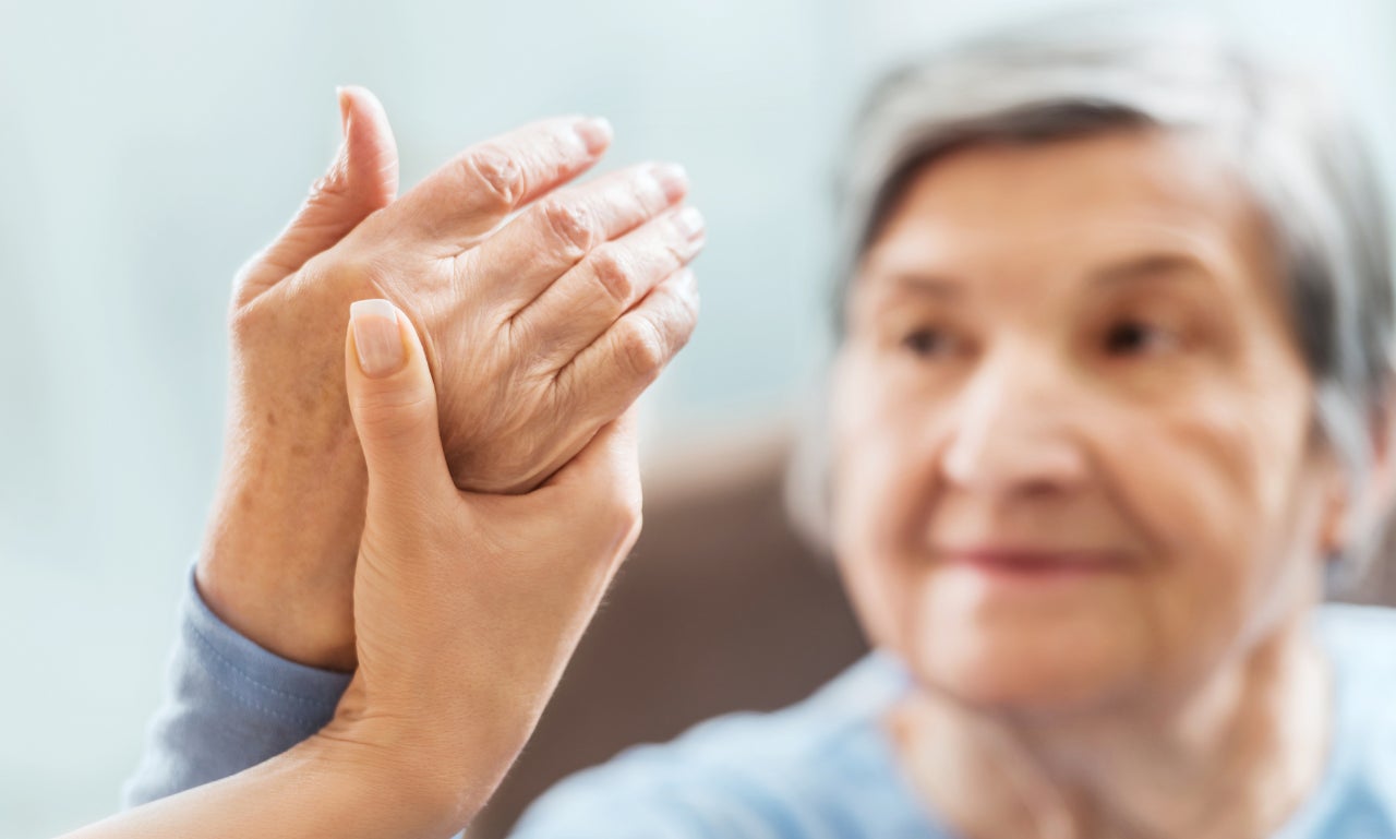 Eine junge Frau hält die Hand einer älteren Dame