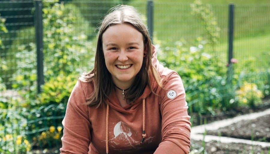 Ein lächelndes Mädchen in einem rosa Sweatshirt und mit glattem Haar.