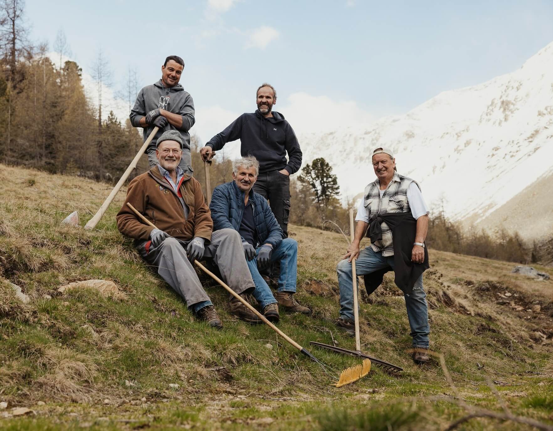 Urban Telser e quattro uomini in posa con attrezzi da lavoro e montagne sullo sfondo