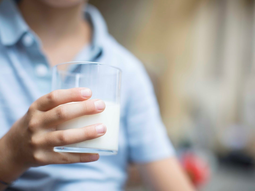 Kinderhand hält ein Glas mit frischer Milch.