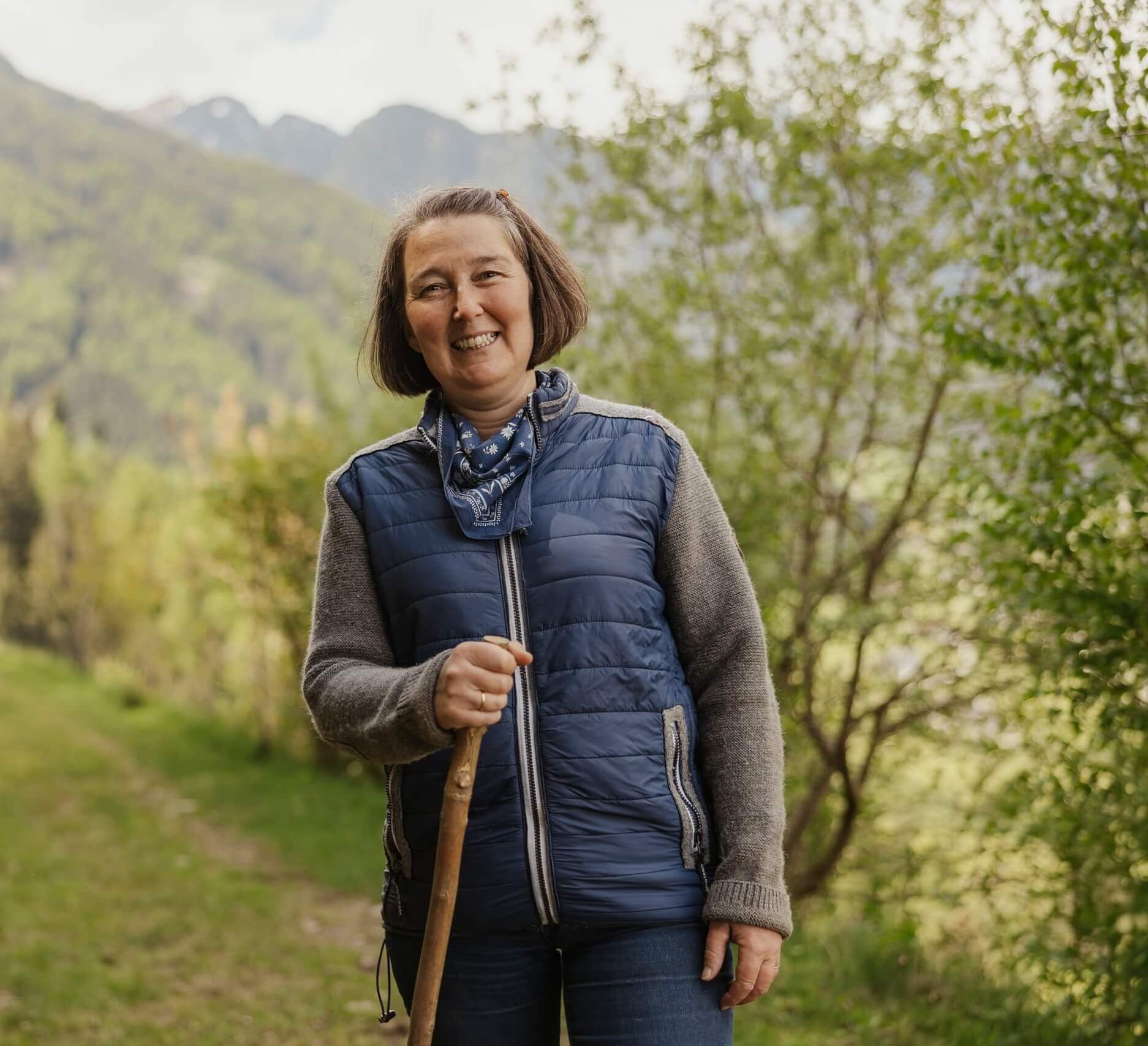 Margareth Vanzetta in posa con un bastone con alberi e montagne sullo sfondo