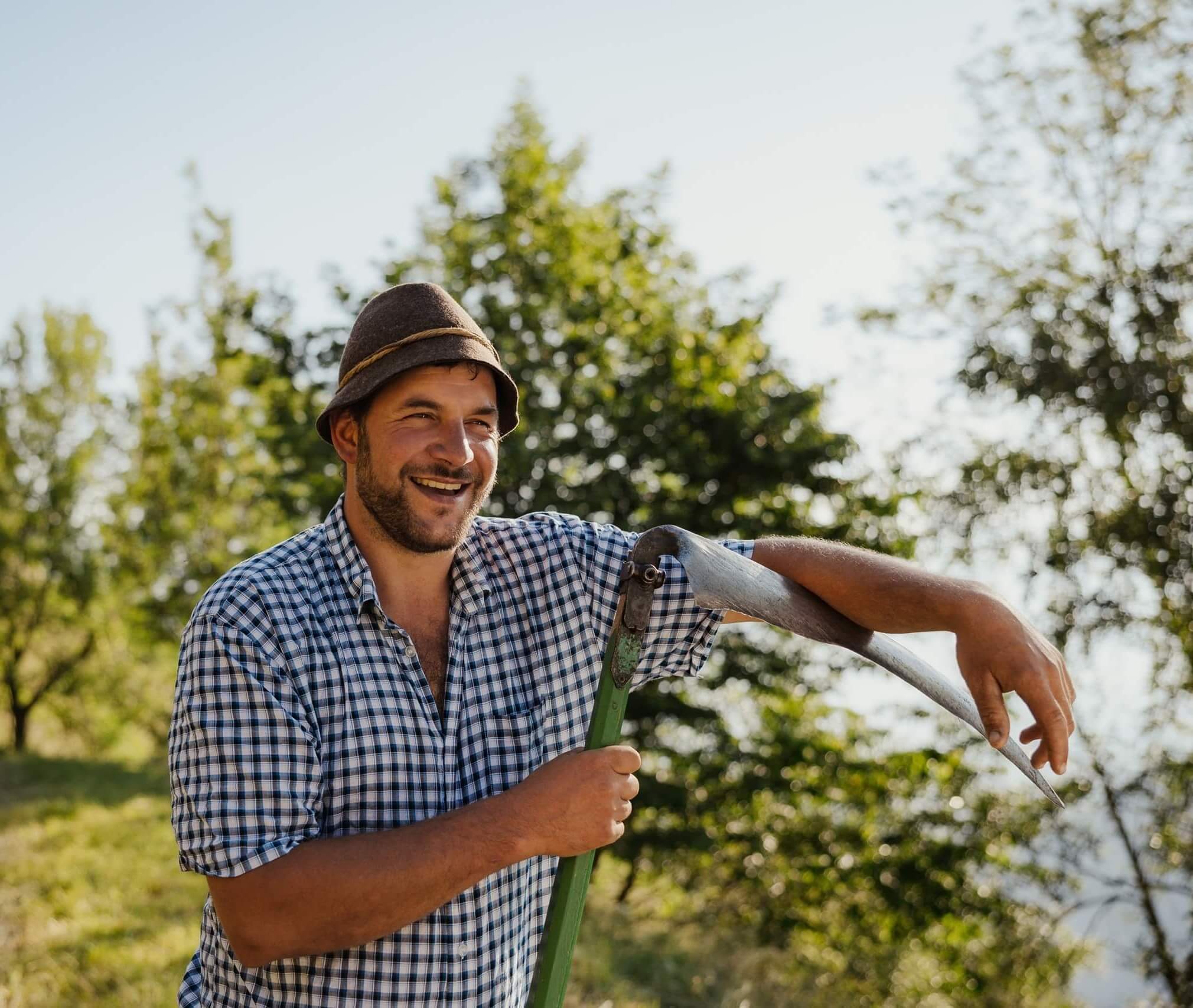 Alex Kohlhaupt sorridente con falce in mano e alberi sullo sfondo