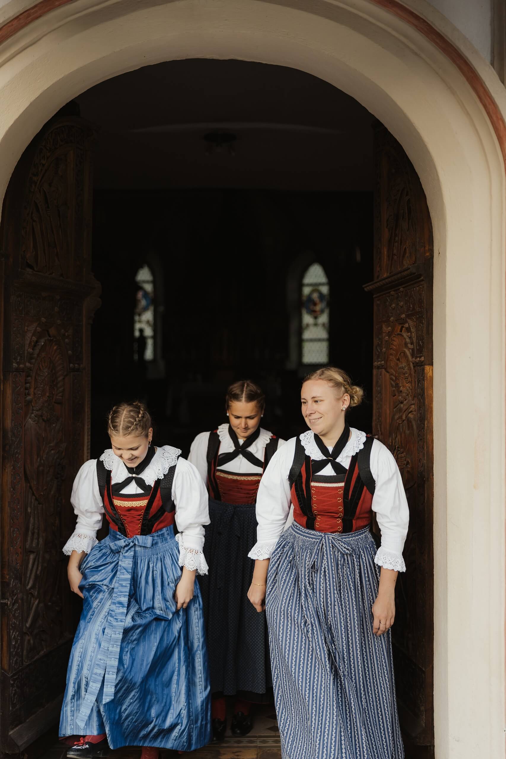 Martina Breitenberger e altre due ragazze in costume tradizionale escono da un portone