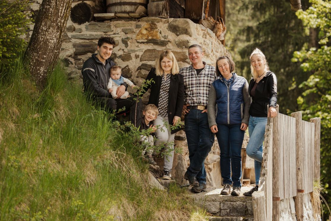 Eine Familie lächelt, während sie vor einer Steinmauer posiert.