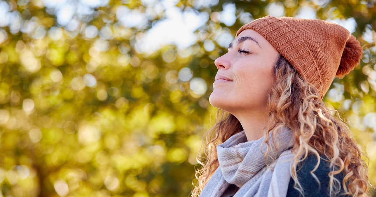 Women in a hat breathing deeply in an outside setting