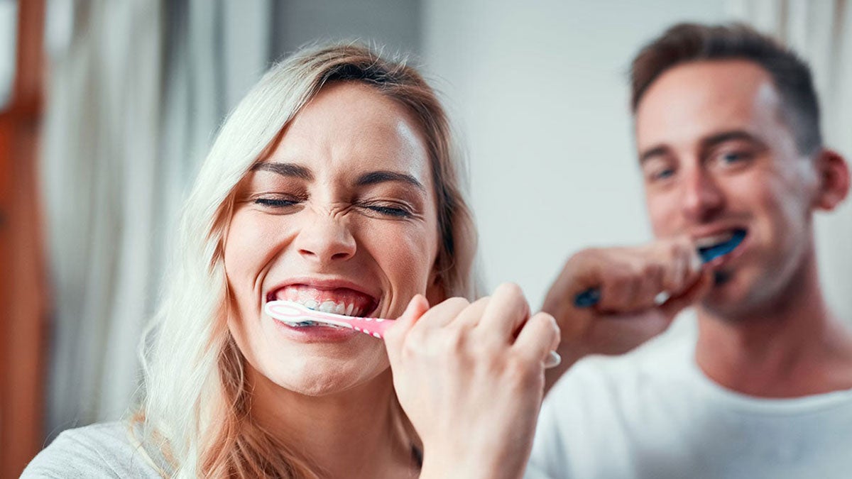 A couple brushing their teeth and smiling