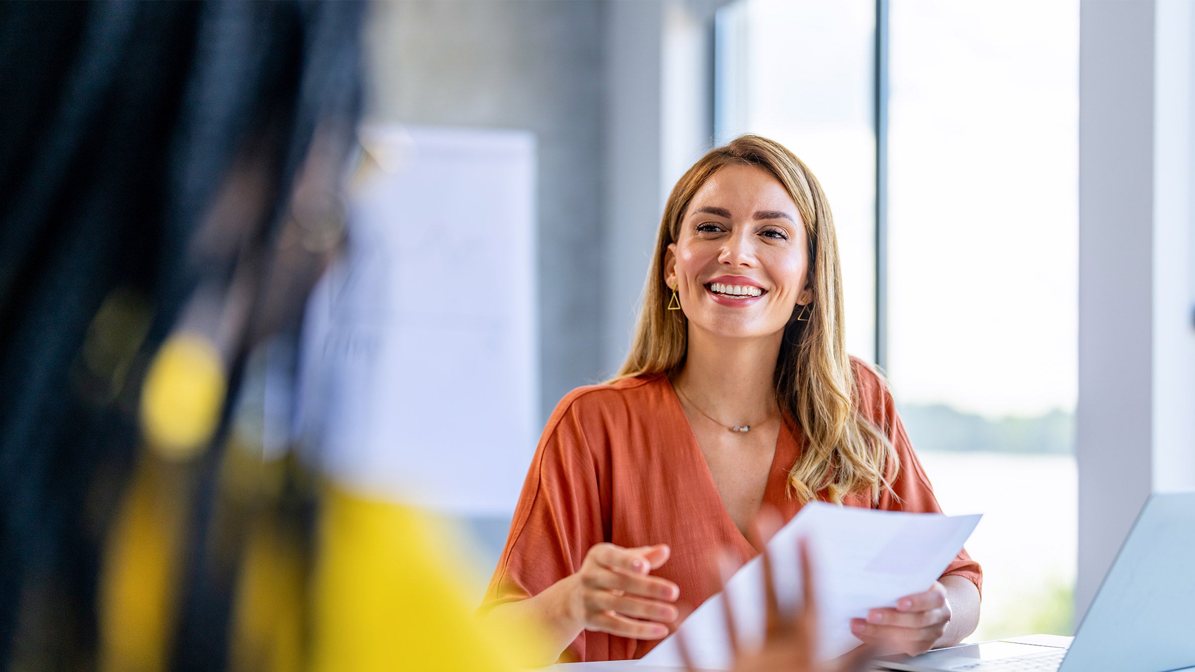 Woman in an orange top holding paperwork