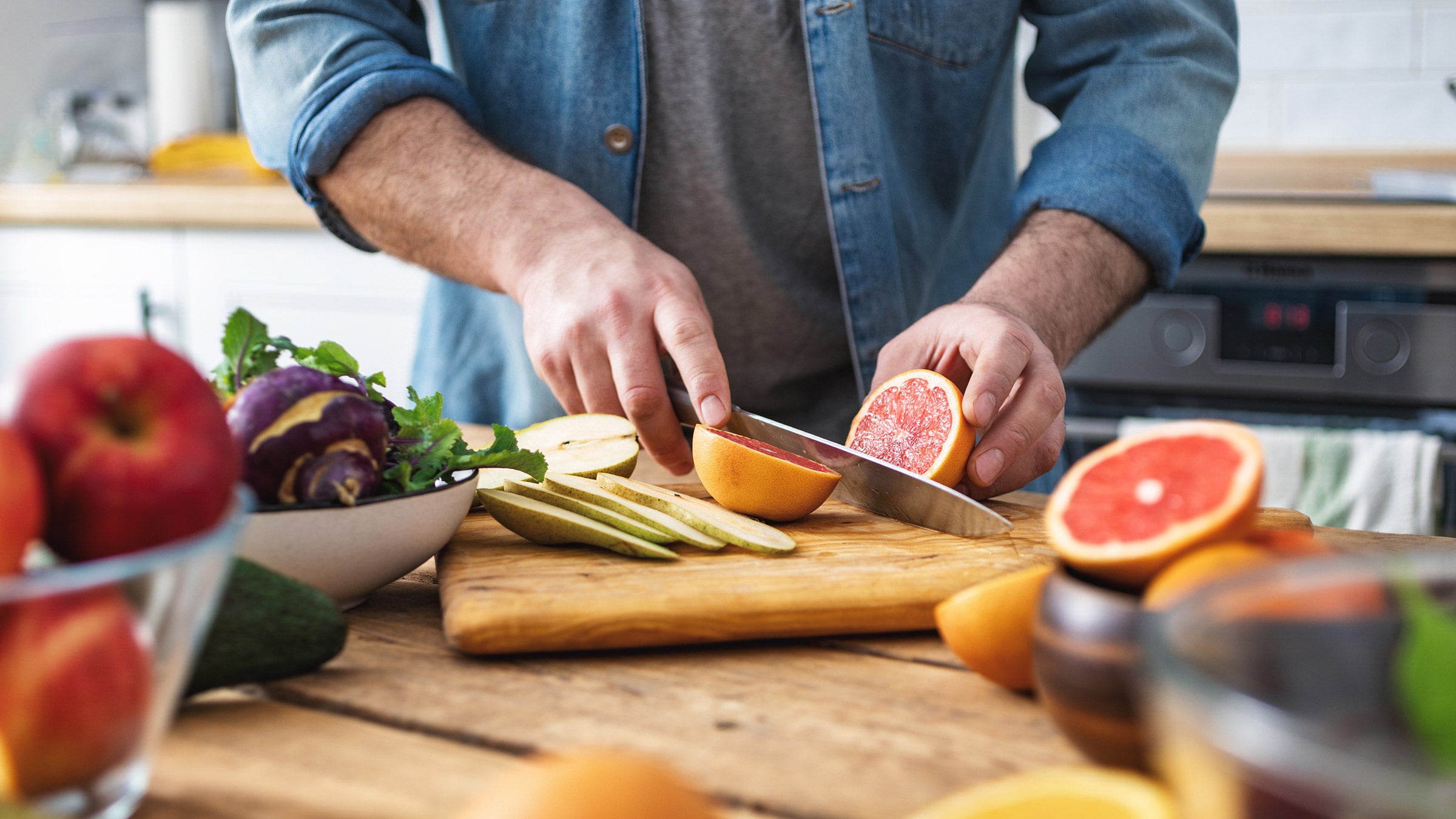 Man cutting grapefruit on a wooden board